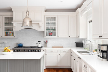 A kitchen detail with cream cabinets, a marble subway tile backsplash, bronze light fixtures, and...