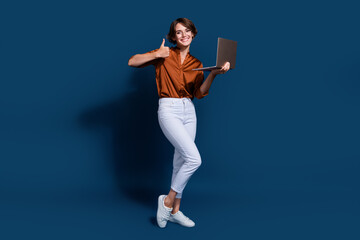 Fototapeta na wymiar Full length photo of cool confident lady wear brown shirt showing thumb up texting modern gadget isolated blue color background