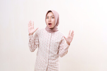 Shocked young asian muslim woman standing while looking at the camera with open mouth. Isolated on white