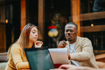 Multicultural business professionals plan business expansion and financial strategies at an outdoor coffee bar, aiming for profit and scalability with angel investors and a strong business plan.