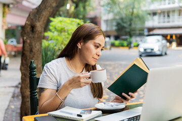Young woman in a cafe drinking coffee and reading a book.