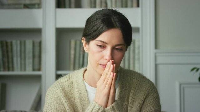 Close-up of upset girl sad tense sitting at home in living room with offended offended expression on her face, worrying about problems. Depressed Frustrated Sad worried young woman. Close up view, 4K