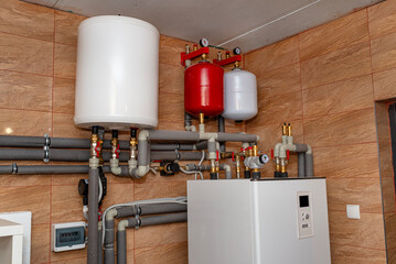 A modern air heat pump installed in the home's boiler room, visible plastic pipes and valves. - obrazy, fototapety, plakaty