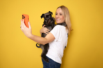Friendship concept. Happy european woman taking selfie with her cute schnauzer dog, looking and...