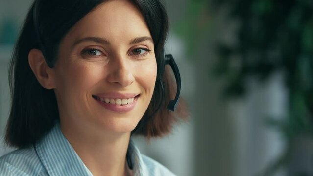 Young woman working in a call center. Happy smiling call center operator answering phone calls wearing headphones. Call center and helpful customer service. Working at customer care. Close up