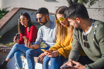 Group of young Caucasian millennials spends time using social networks on smartphones while isolating themselves from real life. New bad habits changing interpersonal relationships