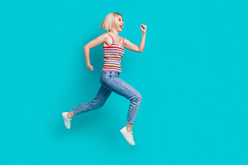 Fototapeta na wymiar Full length photo of charming impressed girl dressed striped tank top running fast jumping high empty space isolated teal color background