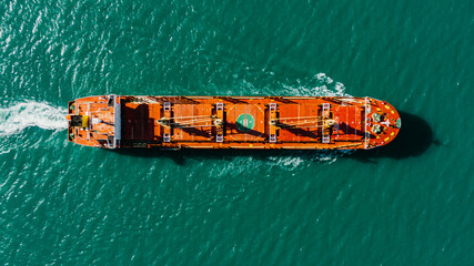 A top-down view of an oil tanker or a large cargo ship sailing on a turquoise sea.