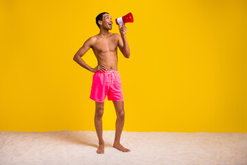 Full length photo of cheerful excited masculine guy screaming announcement bullhorn empty space isolated yellow color background