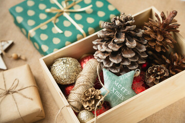 Spruce cones and other decorations for Christmas and New Year are in a wooden box, which is located on the table next to the wrapping of gifts. Getting ready for Christmas.