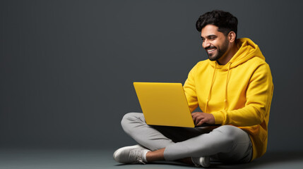 Happy young man working on a laptop against solid background