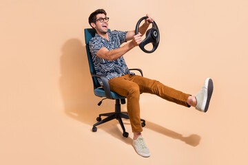 Full body photo of young man learning how to drive holding steering wheel simulation sitting...