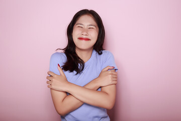 Obraz premium Portrait of a beautiful young woman in a light pink background, happy and smile, posting in stand position, half body photo of nice positive lady crossed arms posing empty space ad isolated.