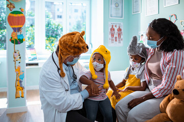 Doctor in Animal Hat Examining Child with Mothers Support at clinic