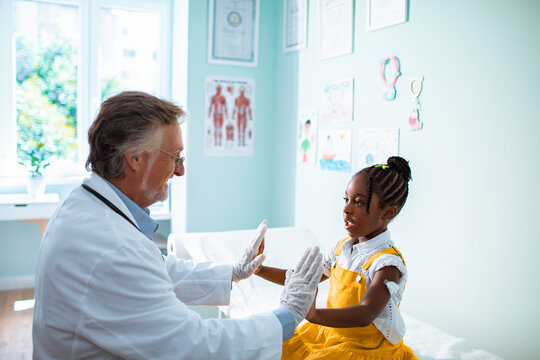 Caring pediatrician give high five with little child in hospital