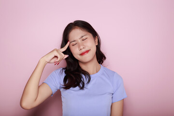 Fototapeta premium Asian woman making a stressed expression Standing alone on a light pink background. Beautiful young woman is feeling stressed.