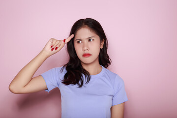 Asian woman making a stressed expression Standing alone on a light pink background. Beautiful young woman is feeling stressed.