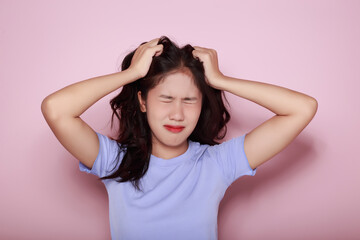 Fototapeta premium Asian woman making a stressed expression Standing alone on a light pink background. Beautiful young woman is feeling stressed.