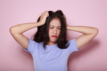Asian woman making a stressed expression Standing alone on a light pink background. Beautiful young...