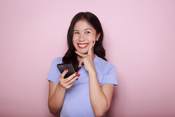 Asian woman cheerfully posing with a mobile, A beautiful young woman is feeling cheerful and happy., half body photo of nice positive lady, Portrait of a beautiful young woman in pink background,