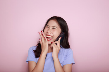 Asian woman cheerfully posing with a mobile, A beautiful young woman is feeling cheerful and happy., half body photo of nice positive lady, Portrait of a beautiful young woman in pink background,
