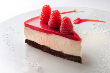 Slice of cheese cake with raspberry cream and with raspberries on top