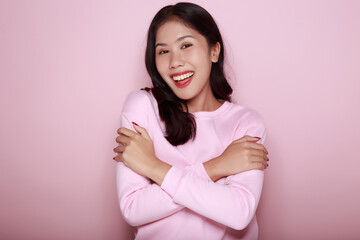 Portrait of a beautiful young woman in a light pink background, happy and smile, posting in stand position, half body photo of nice positive lady crossed arms posing empty space ad isolated.
