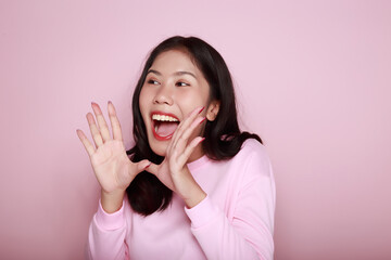 Portrait of a beautiful young woman in a light pink background, happy and smile, posting in stand...