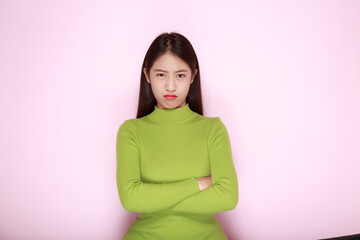 Obraz premium Asian woman making an angry expression, Portrait of a young woman in a light pink background.
