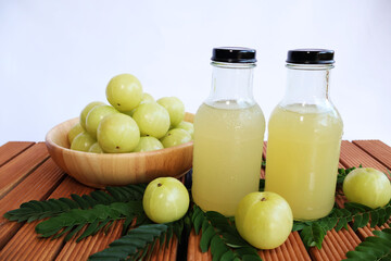 Gooseberry juice in a bottle and fruit in a wooden bowl

