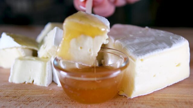 Brie type of cheese. Camembert cheese. Fresh Brie cheese and a slice on a wooden board with nuts, honey and leaves. Italian. French cheese.