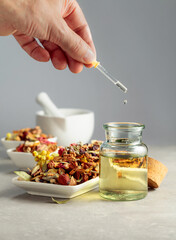 Dropping essential oil or herbal tincture into a glass bottle.