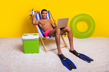 Full length photo of good mood positive masculine guy sitting lounge winning game modern gadget isolated yellow color background