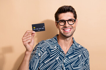 Photo of intelligent clever man dressed print shirt in eyewear demonstrate plastic debit card in...