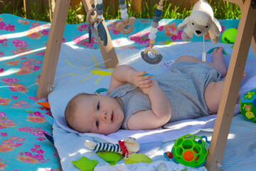 Baby auf einer Decke auf dem Rasen mit Spielzeug