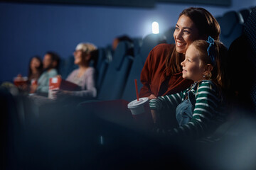 Happy mother and daughter enjoying in movie projection in theater