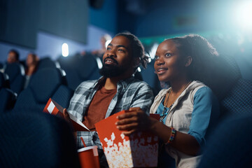 Happy black couple watching movie in theater.