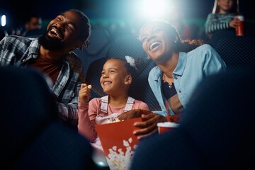 Happy black family has fun during movie projection in theater.