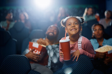 Happy black girl enjoying while watching movie in cinema. - obrazy, fototapety, plakaty