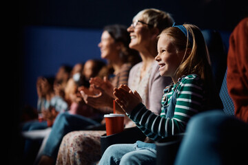 Happy girl applauding after movie projection in cinema.