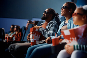 Happy black man and his family watching 3D movie in cinema.