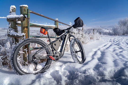 Cochrane Alberta Canada, November 16 2023: A fat bike leaning up against a barbed wire fence after a recent snowfall at Glenbow Ranch Provincial Park.
