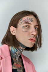 portrait of handsome young man with stylish tattoos on face looking at camera, fashion concept