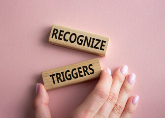 Recognize triggers symbol. Concept words Recognize triggers on wooden blocks. Businessman hand. Beautiful pink background. Business and Recognize triggers concept. Copy space.