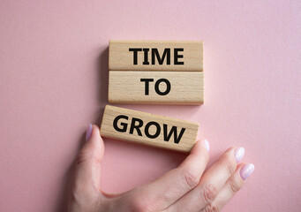 Time to Grow symbol. Concept word Time to Grow on wooden blocks. Businessman hand. Beautiful pink...