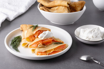 Pancakes with salmon, sour cream and greenstuff. Thin, not sweet blinchiki stuffed with red fish. Feast of Maslenitsa