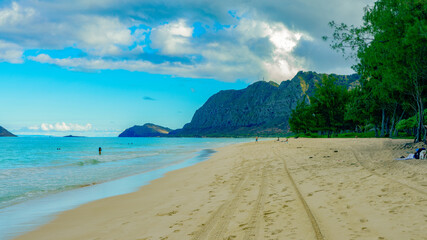 Footprints and tire tracks in the sand at uncrowded Waimanalo Beach, Oahu.