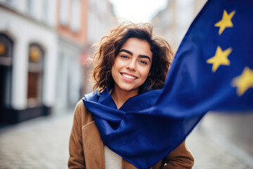 Smiling young Hispanic woman immigrant  posing in the street with an European Union flag.  - obrazy, fototapety, plakaty