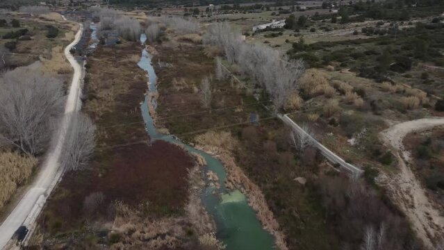 Low flight over the narrow Albaida river and fields in autumn in Bellus, in Valencia province, Spain