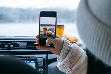 woman take picture of burger at car dashboard